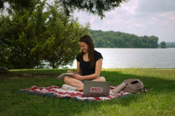 A student working on a laptop in a park.